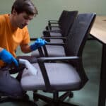 Hard-working janitor is deep-cleansing chairs with vacuum-cleaner